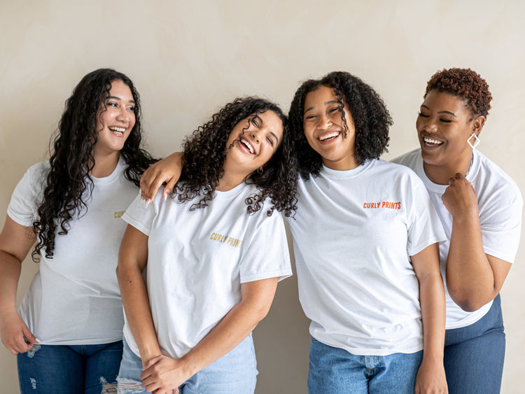 curly hair women smiling and laughing in curly prints white summer tee